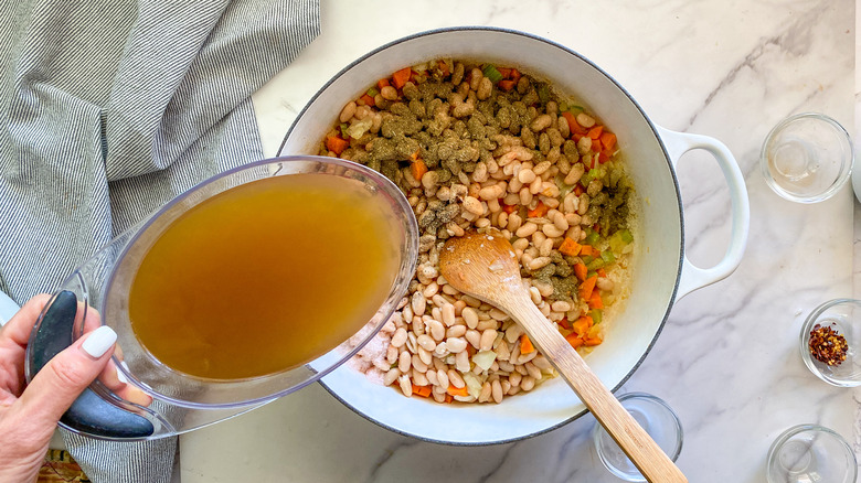 adding broth to pot