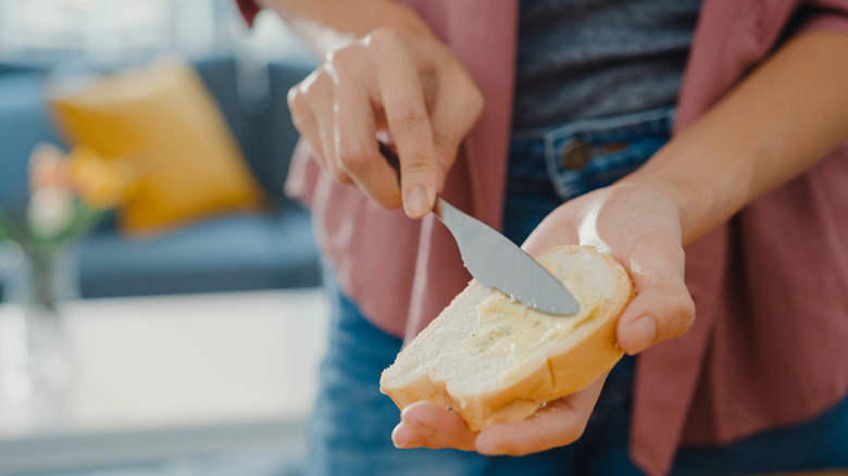 Person spreading butter on bread