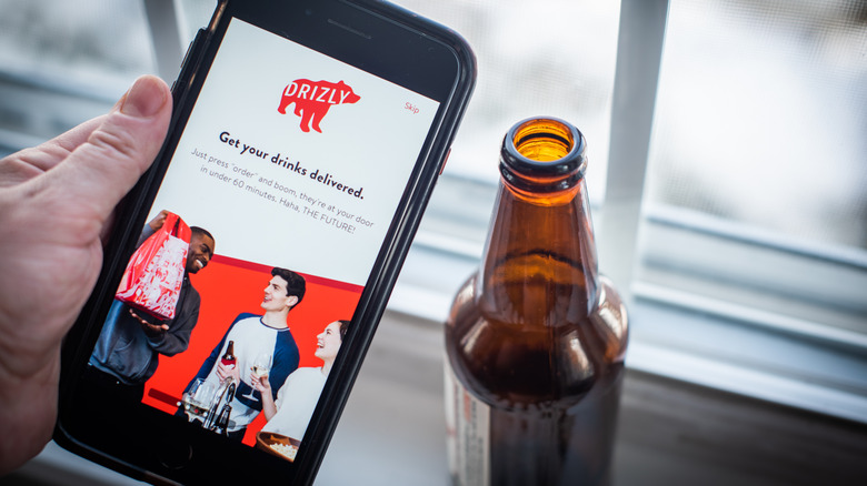 phone with Drizly app held next to open bottle of beer