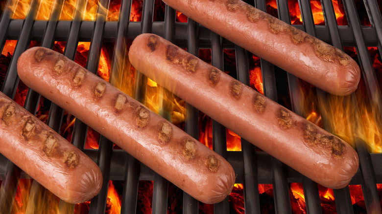 Hot dogs being grilled over flame