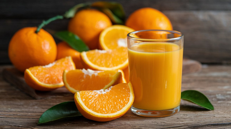 a glass of orange juice with halved fresh oranges around it