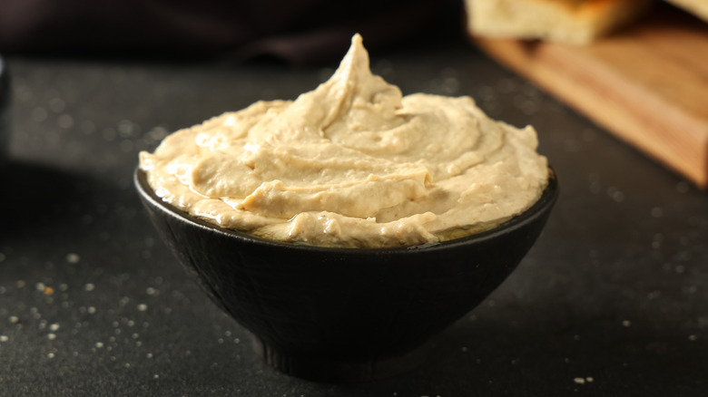 Bowl of plain hummus on black background