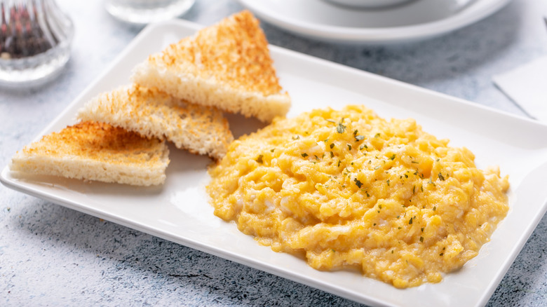 Scrambled eggs with toast on white plate