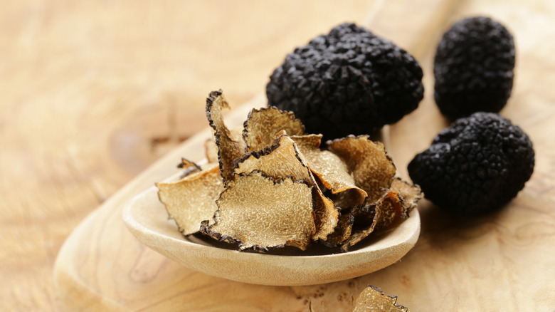 Sliced black truffles next to whole truffles