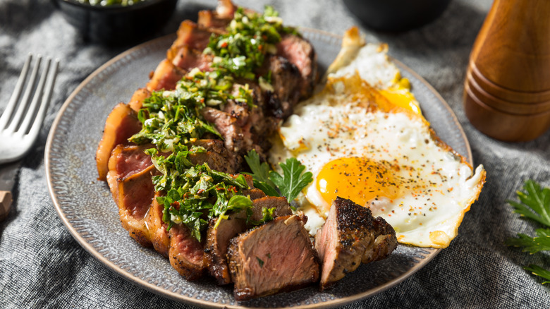 steak and eggs served with chimichurri sauce
