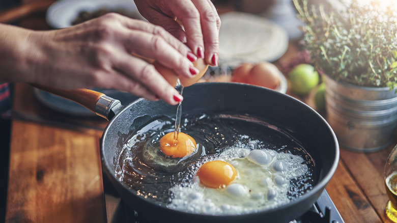 person frying egg in pan