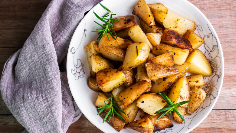 Bowl of roasted potatoes with rosemary on a table
