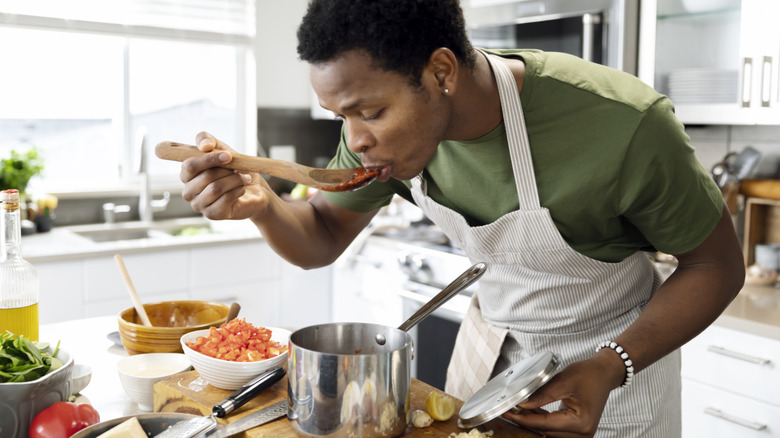 a home cook tasting sauce in their kitchen