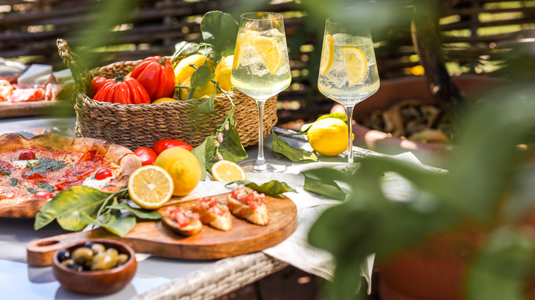 limoncello spritzers next to an array of Italian food, fresh tomatoes, and lemons