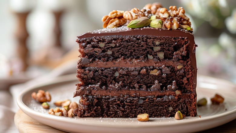 Slice of chocolate cake with chocolate frosting layers and nuts