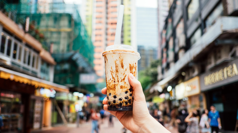 A hand holding a plastic cup of bubble tea.
