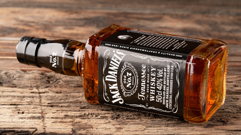 A Jack Daniel's bottle lying on a wood surface.