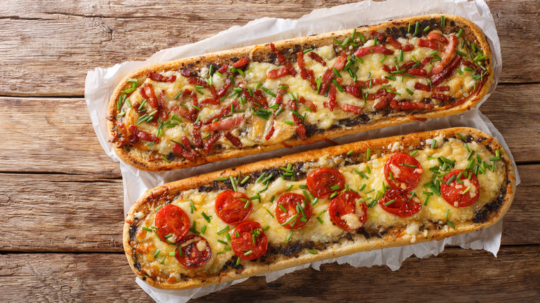 Two French bread pizzas on wooden table