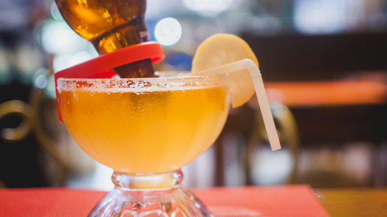 Margarita topped with a beer bottle with salted rim and lemon slice garnish