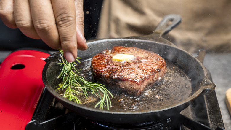 Steak in a cast iron pan with butter and rosemary