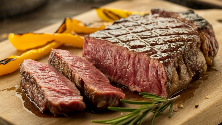 A sliced ribeye steak on a wooden board