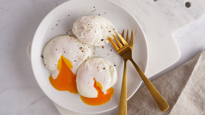 Two forks and three seasoned poached eggs in a bowl