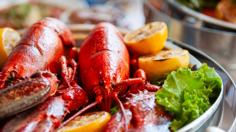 Two cooked lobsters on a plate with lemons