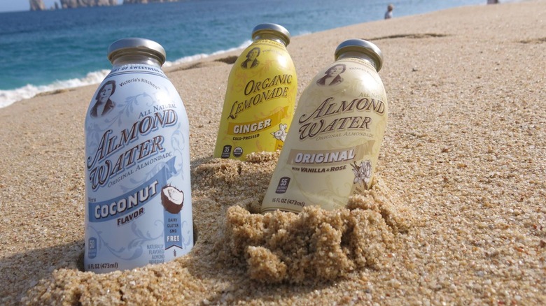 Bottles of Victoria's Kitchen Almond Water on a beach