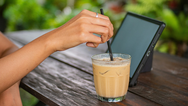 person stirring iced coffee