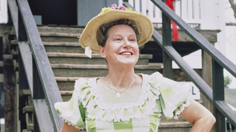Minnie Pearl wearing straw hat with tag hanging down in a green and white checkered dress