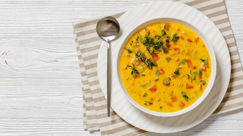 Beer cheese soup in white bowl with a spoon