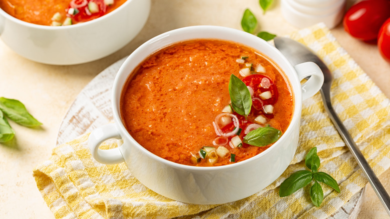 Gazpacho served in a white bowl with basil leaves