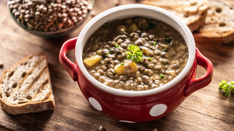 Lentil soup with bread on a wood background