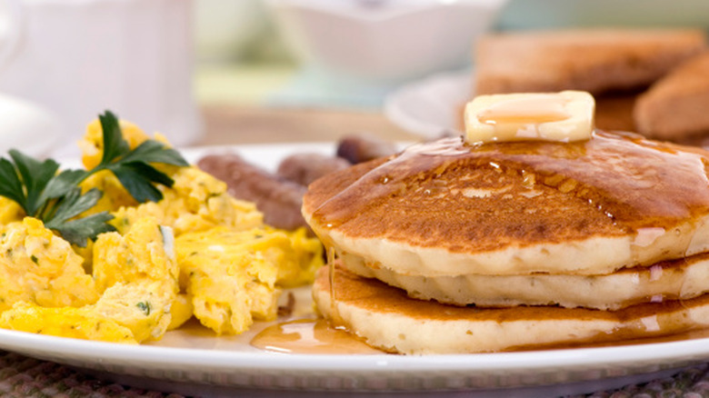 A plate of pancakes and scrambled eggs.