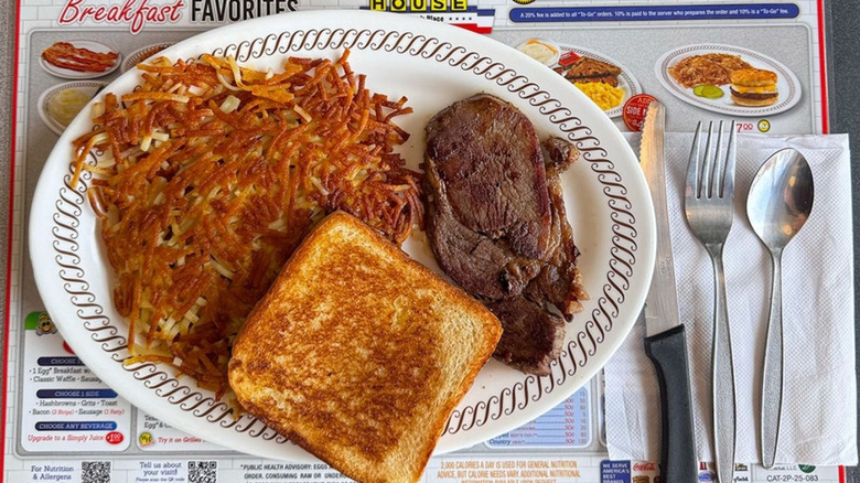 Steak, hashbrowns, and a piece of toast on a oval plate at Waffle House.