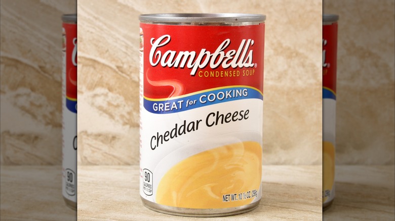 A ladle pouring cheddar cheese sauce into a bowl.