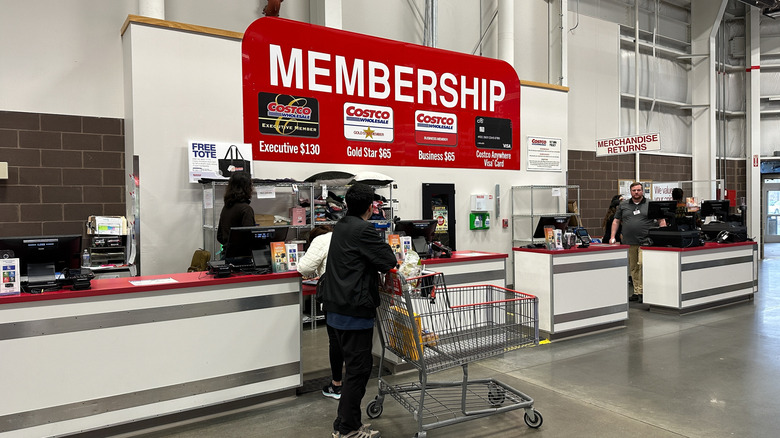 A person behind a cart waits at a Costco Membership counter