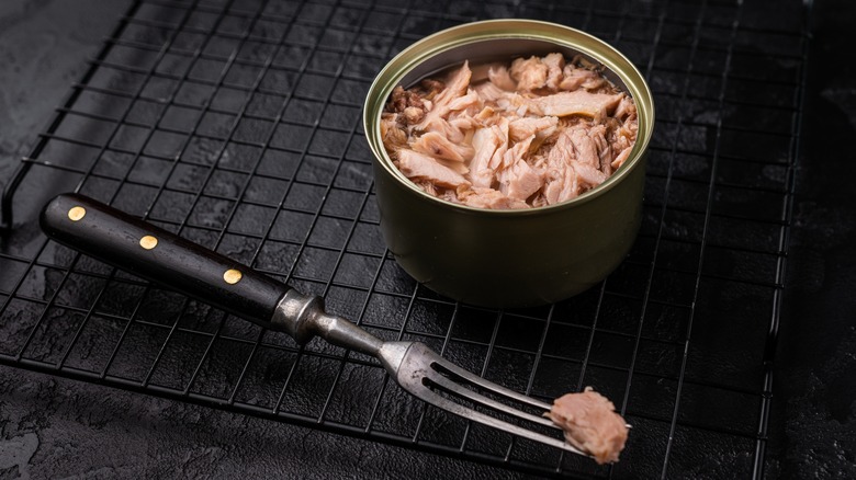 Open can of tuna and fork on a wire rack