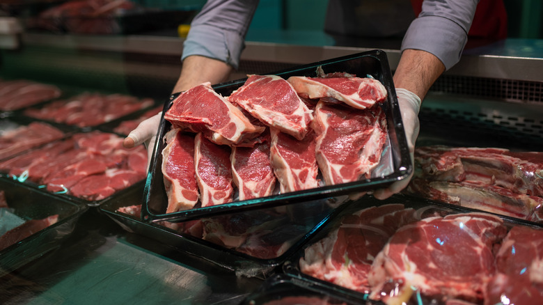 A pack of steaks being pulled from a butcher's counter