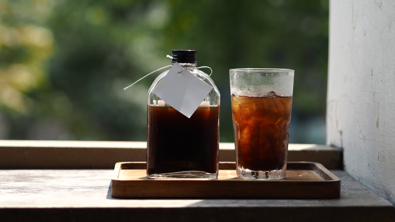 cold brew coffee on a tray next to a clear glass bottle of coffee.
