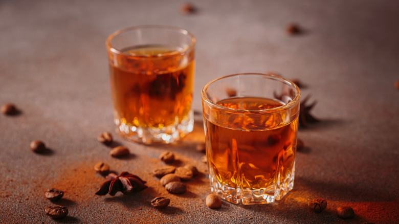 two shot glasses with coffee beans scattered around them.