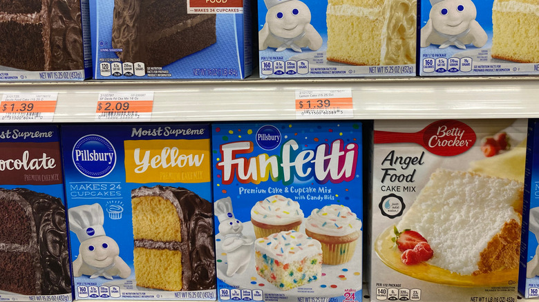 Trays of boxed cake mixes in the baking aisle of a grocery store