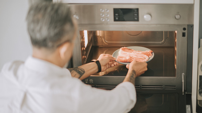 Frozen pork going into a microwave