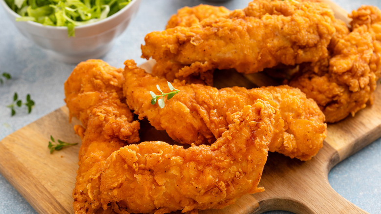 Chicken tenders on a wooden cutting board