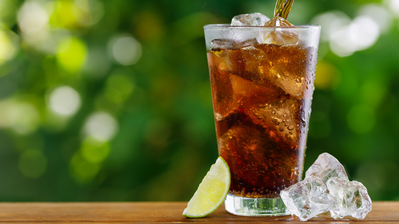cola poured into glass with ice outside