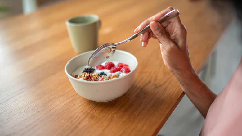 woman eating oatmeal with fruit and granola