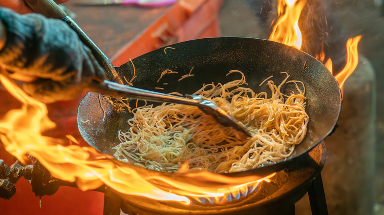 Chef frying Pad Thai noodles in a wok