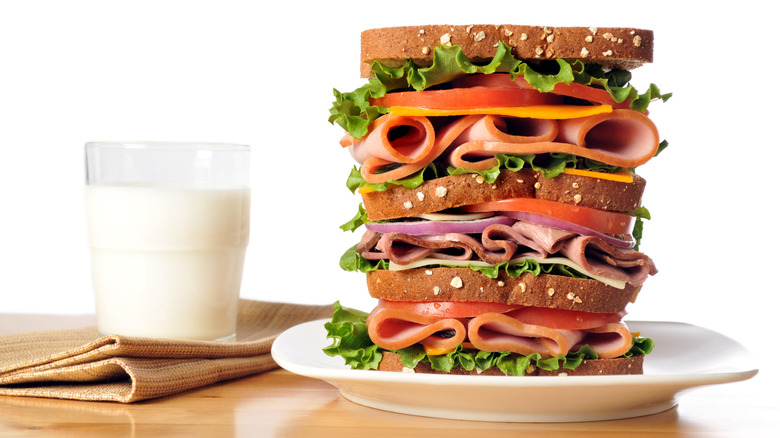 Dagwood sandwich on a plate with a glass of milk