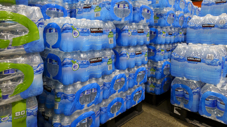 Bottles of Kirkland Signature purified drinking water are stacked on a Costco warehouse floor