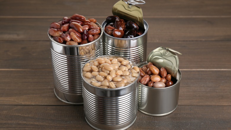 Four opened tin cans with varieties of beans