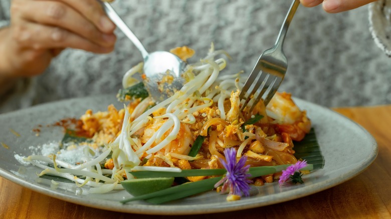 Person eating pad Thai at a restaurant