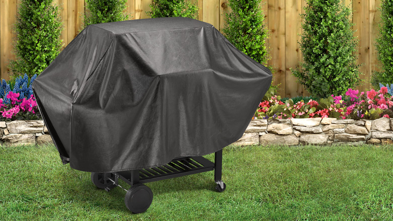 A covered grill in a backyard.