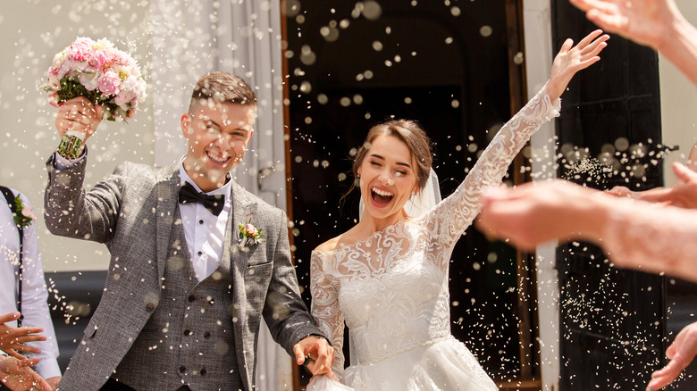 rice thrown in air over couple leaving their wedding ceremony
