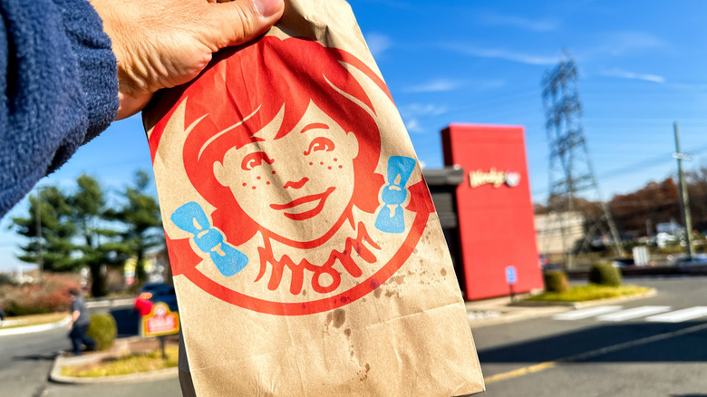 A hand holds a Wendy's food bag.