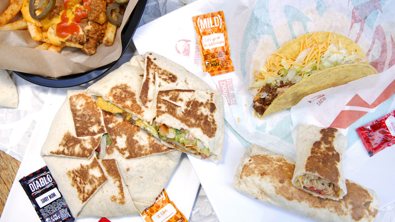 Several Taco Bell food items surrounded by Taco Bell hot sauce